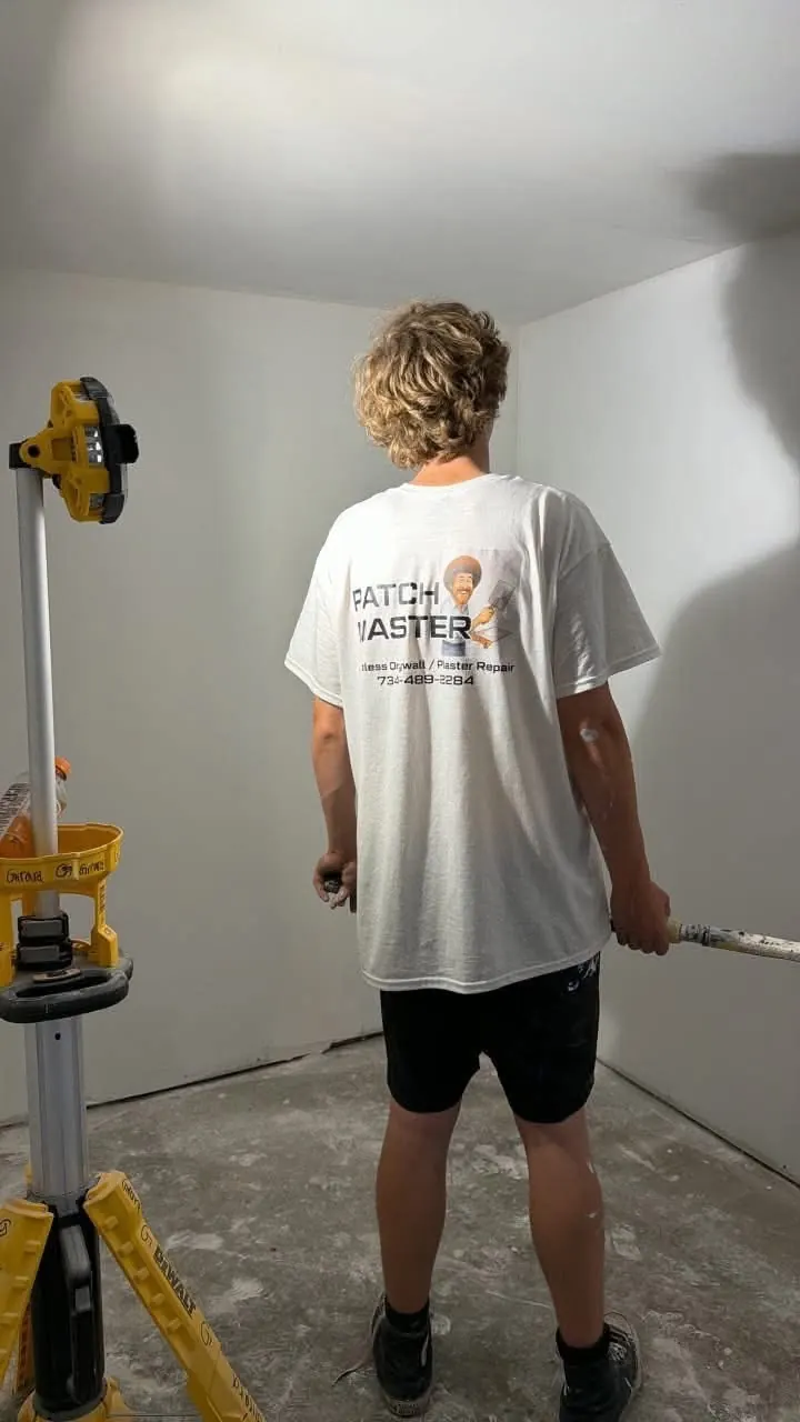 Jonas, Jeremy's son, working in a room with a laser level and a pole sander
